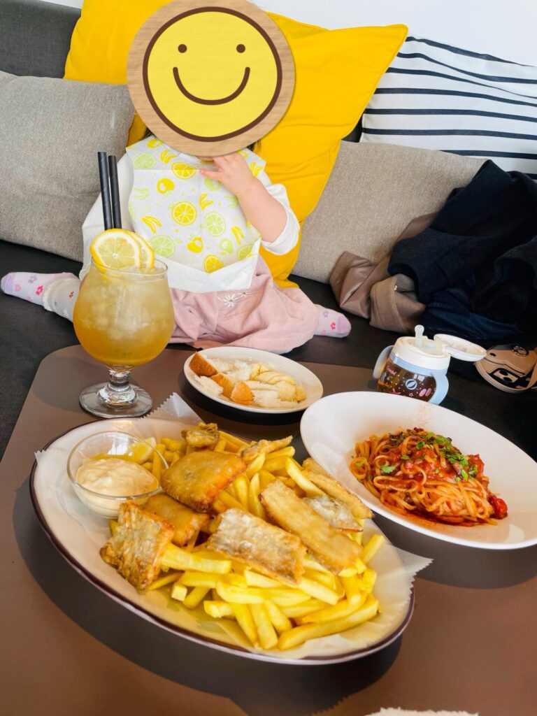 カフェのソファ席で料理と一緒に写る子ども