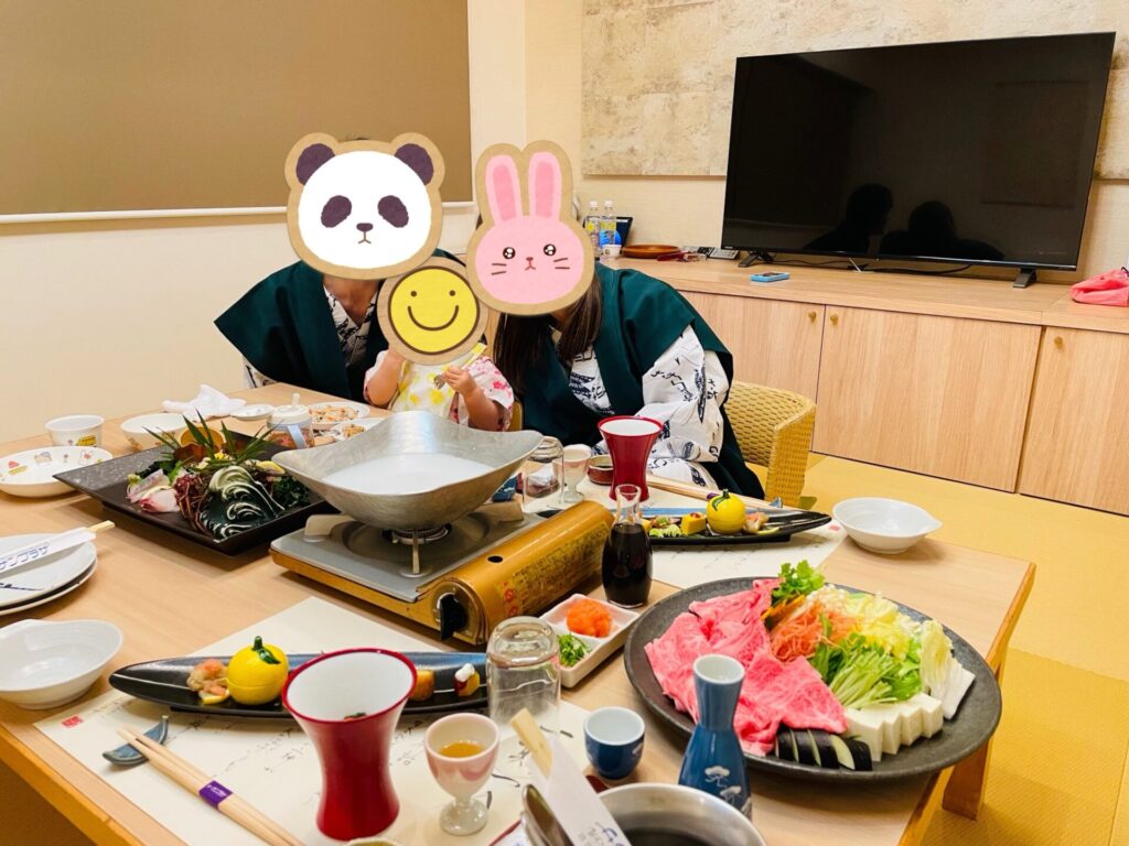 旅館の部屋で夕食を囲む家族
