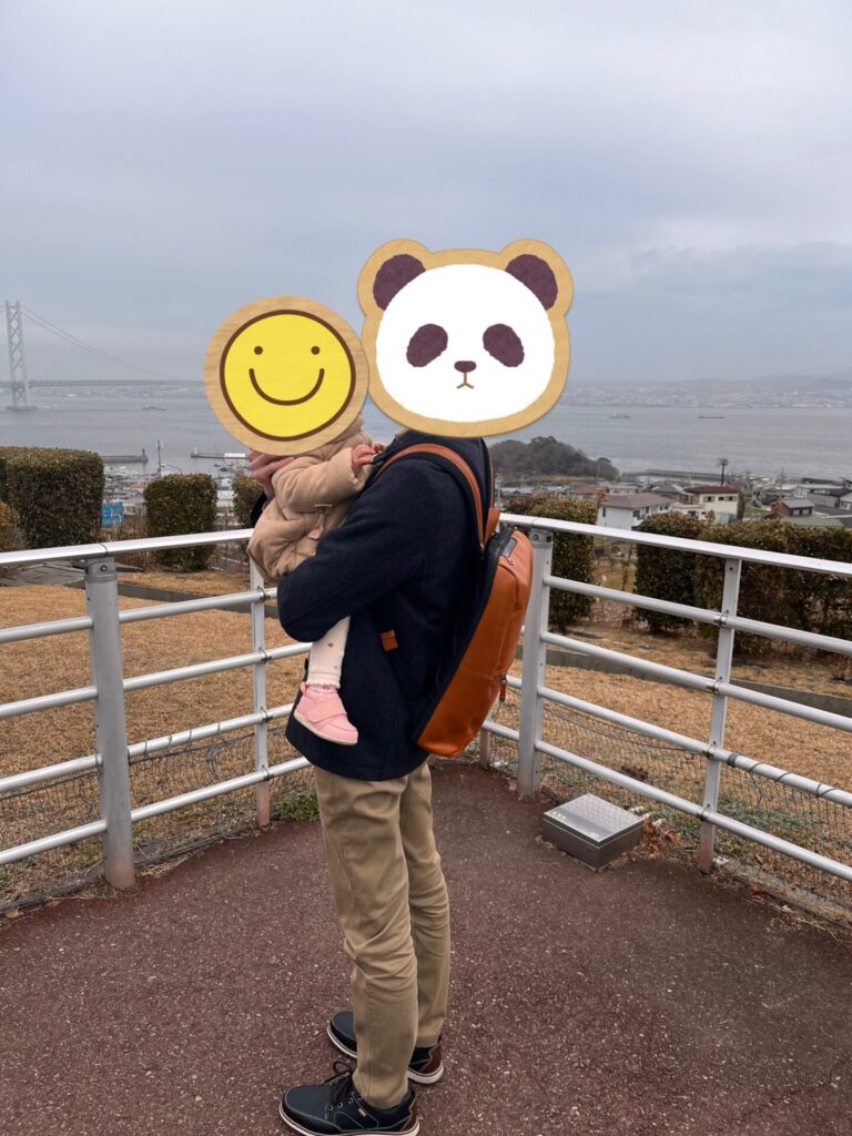 海を背景に子どもを抱っこして立つ父親