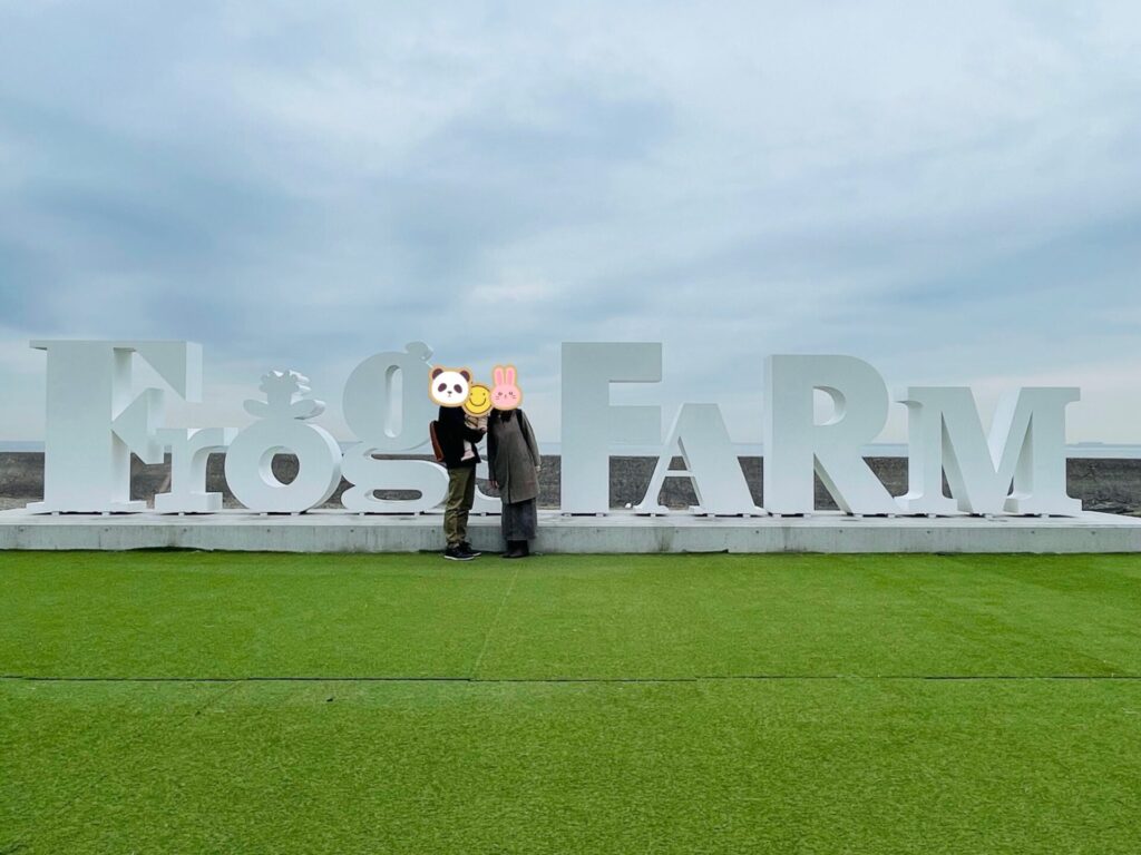 Frog FARMの大きなモニュメント前で立つ家族