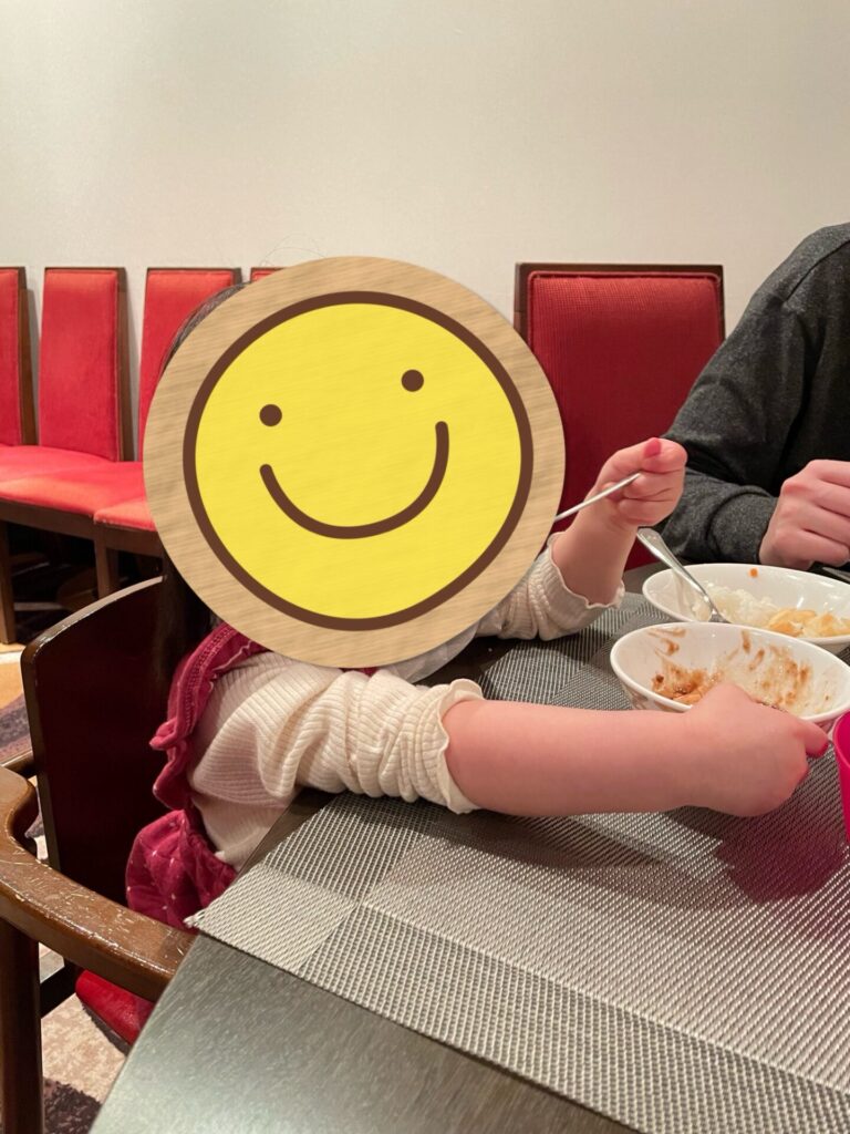 レストランで食事中、テーブルに座る子どもがスプーンを持っている