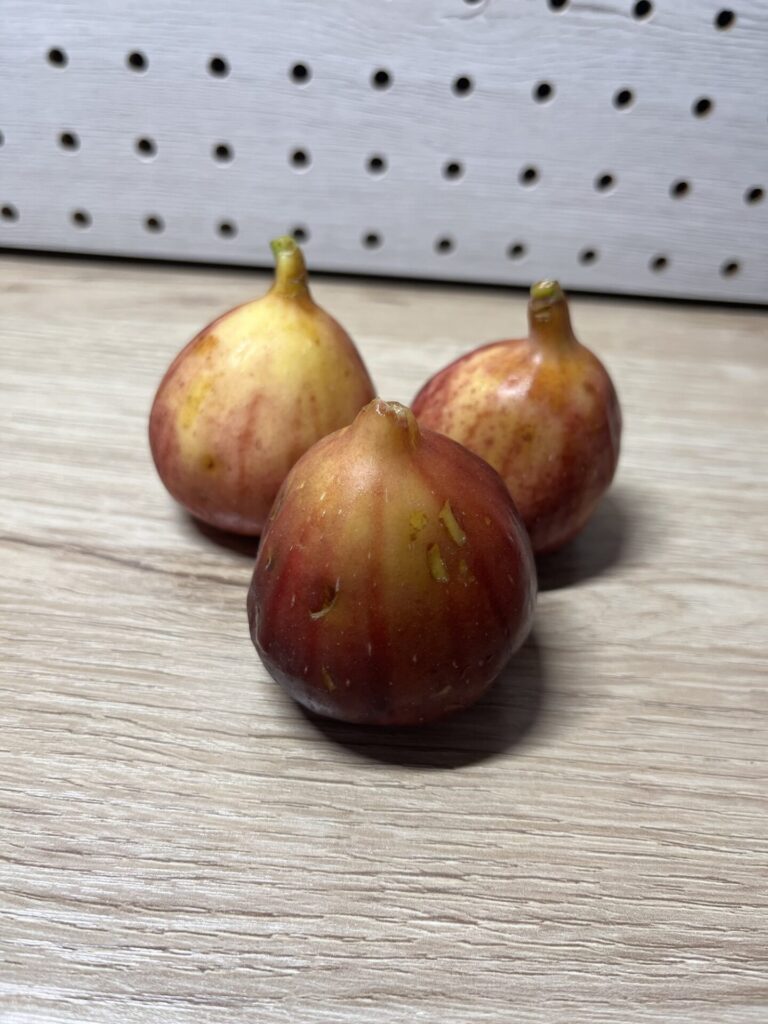 木目の台に置かれた3つのイチジク