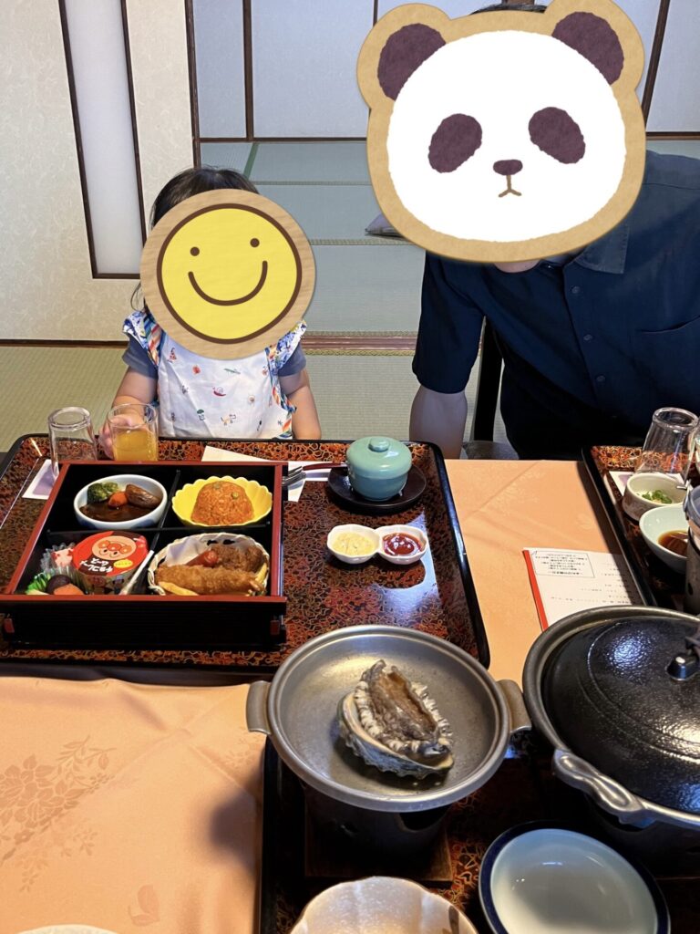 鷲羽グランドホテルの部屋食で、鮑の踊り焼きとお子様ランチが並んでいる食事風景(子どもと大人が座っている、顔はスタンプで隠れている)