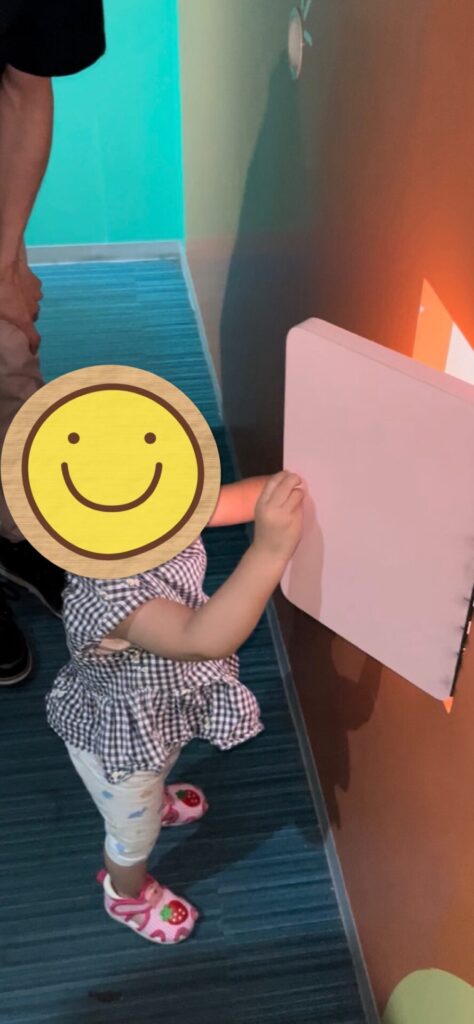 子どもが壁に設置された仕掛けを手で触って遊んでいる様子