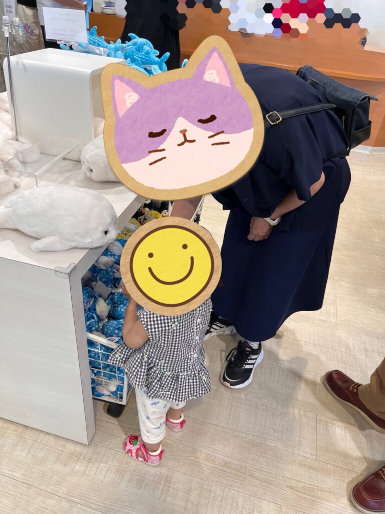 水族館のお土産売り場で、子どもがおばあちゃんと一緒にぬいぐるみを見ている場面