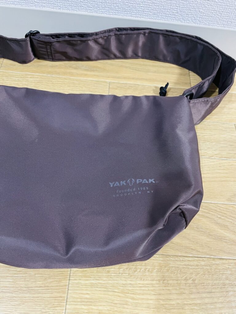 ブラウンカラーのURBAN RESEARCH DOORS別注 撥水ショルダーバッグS。床に置いた状態で、バッグ表面とYAKPAKロゴが見える