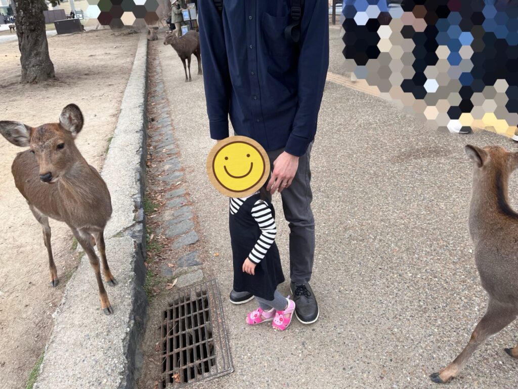 奈良公園で鹿の近くに立つ娘と父親の様子