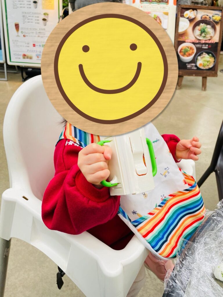 フードコートでベビーチェアに座り、持参したベビーフードを食べている子どもの様子