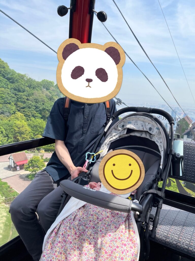ロープウェイに乗りベビーカーの子どもと一緒に過ごす男性