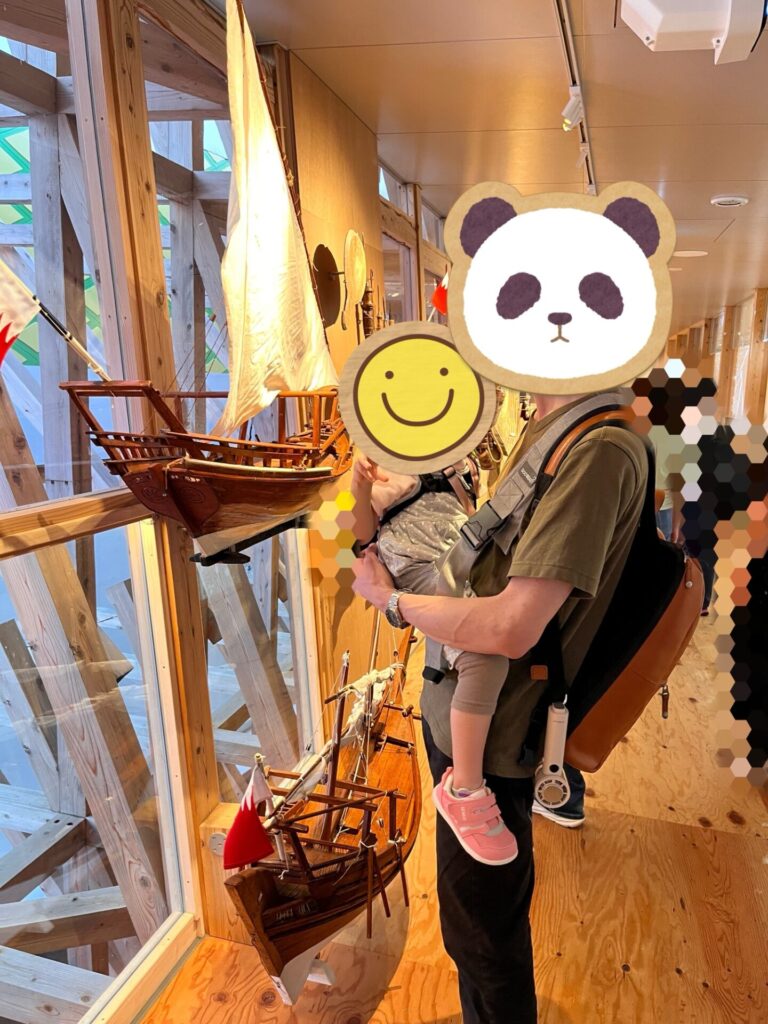 展示された木製の船模型を眺める子どもと父親