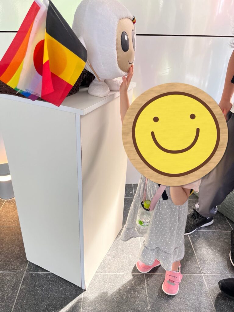 ベルギー館の入口でキャラクターと旗を手にした子ども