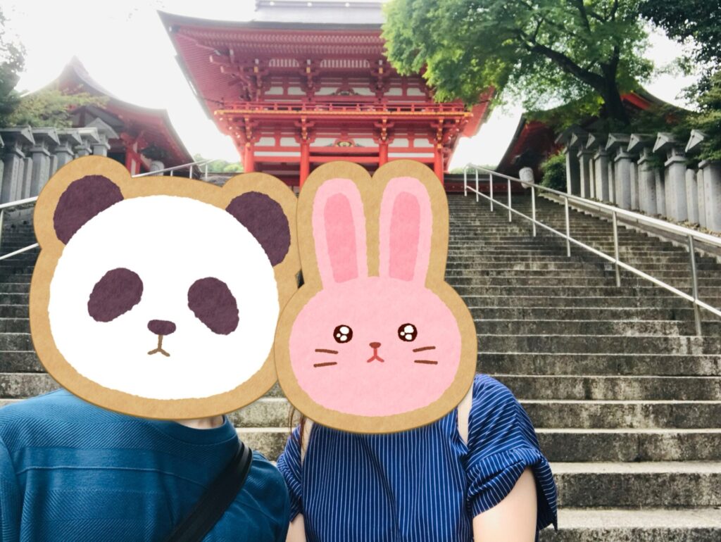 近江神宮の朱色の楼門を背景に、階段前で撮影した夫婦の写真。