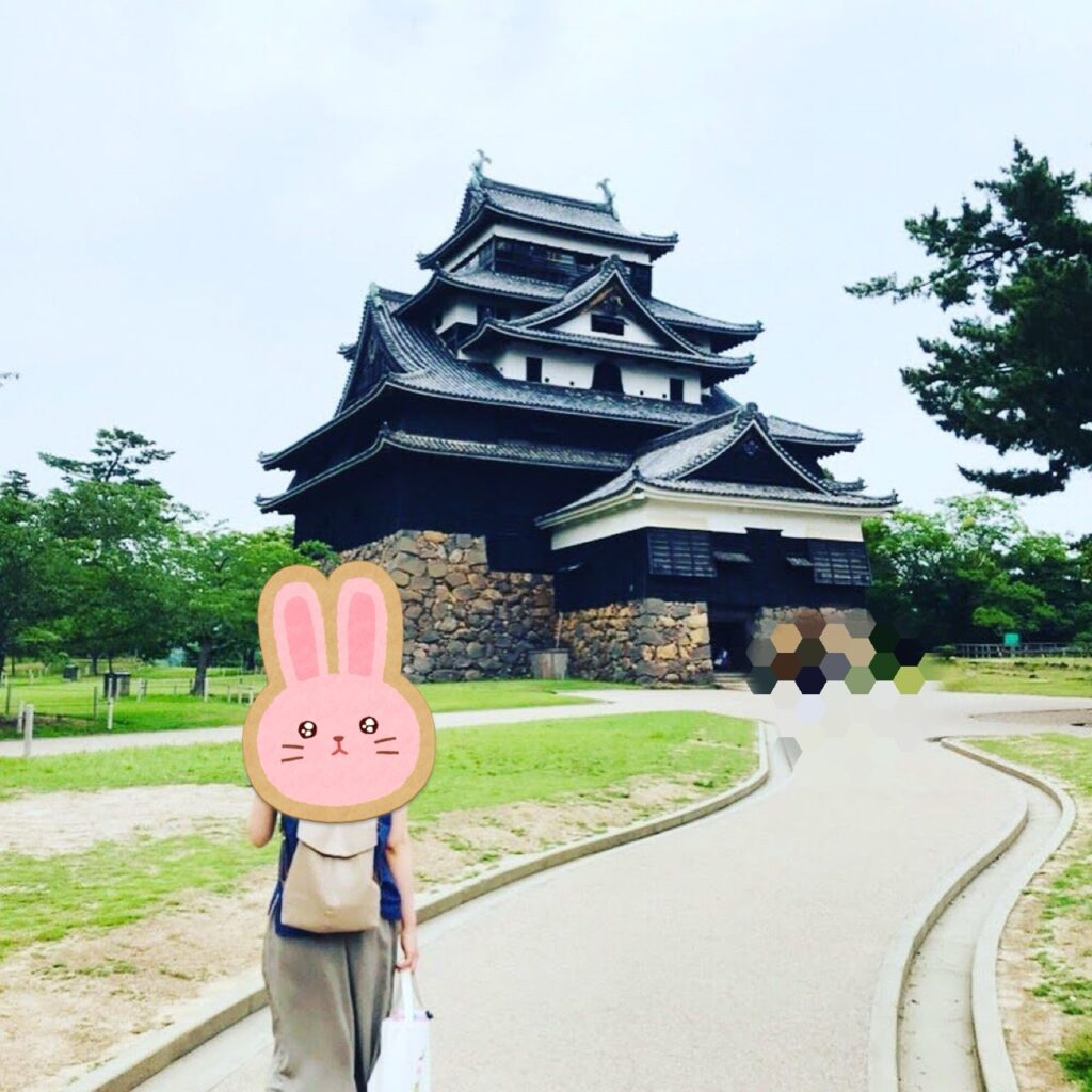 松江城の前を散策する様子。黒塗りの天守と石垣が映える夏の風景。
