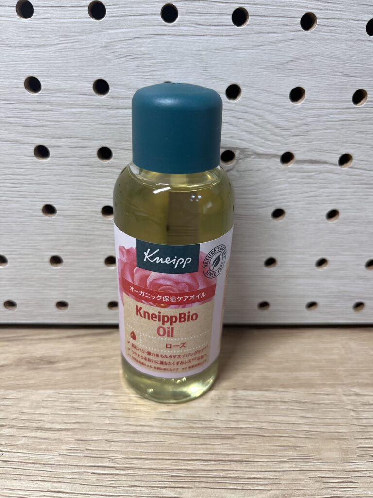 透明ボトルに入ったクナイプのビオオイル（ローズ）が木目の台に置かれている。