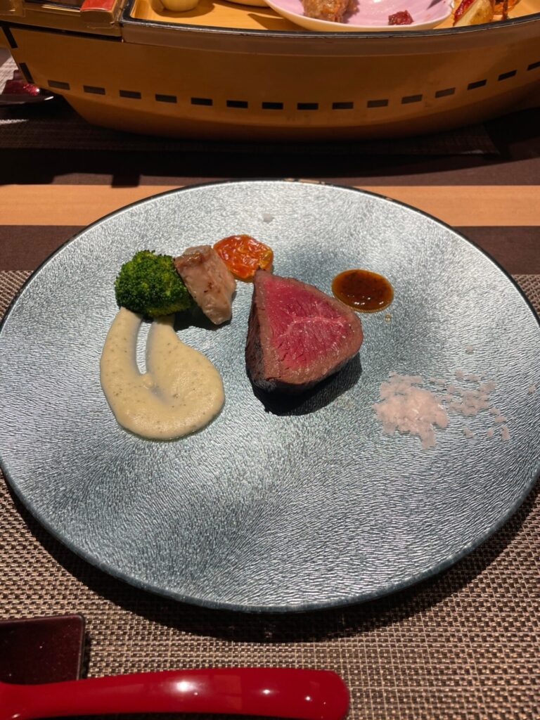 夕食の肉料理。赤身ステーキと付け合わせの野菜が盛り付けられている。