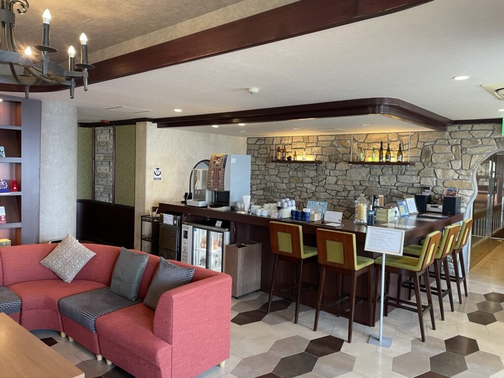 ホテル萬波のラウンジスペース。ソファ席とドリンクカウンターが並び、コーヒーやココアがセルフサービスで利用できる。
