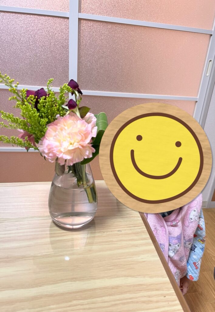 パパと3歳の娘が選んでくれた小さなブーケ。ピンクと紫の花がガラスの花瓶に生けられ、テーブルの上に飾られている。