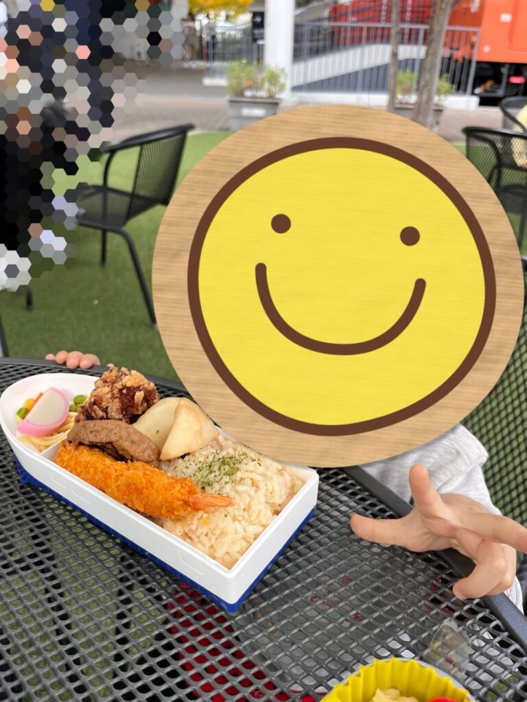 テーブルの上に並ぶ新幹線型ランチボックスを子どもが手にしている様子。