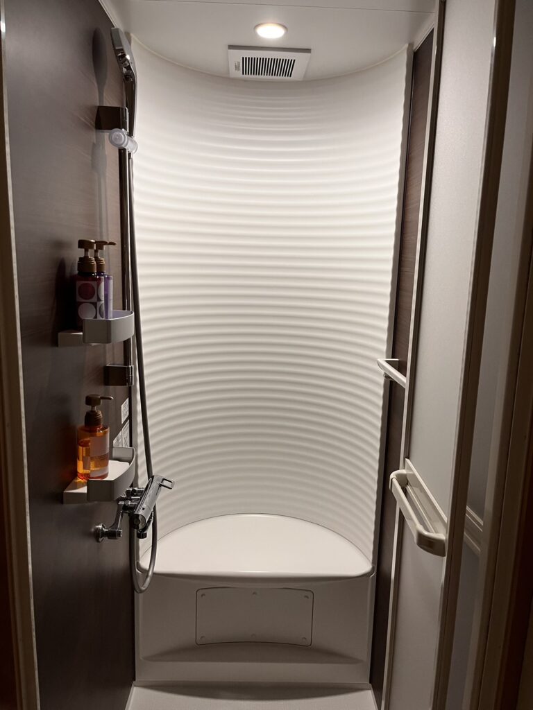 カーブした白い壁が特徴のホテル萬波のシャワールーム。