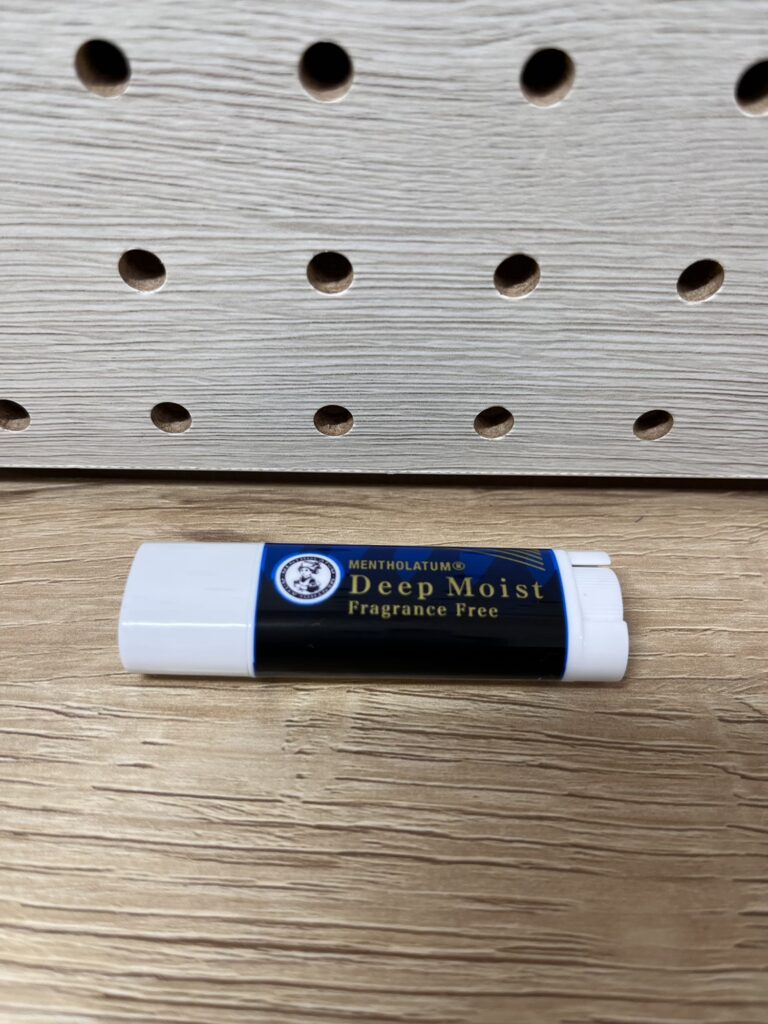 スリムタイプのリップクリームを木目の上に置いて撮影した写真。