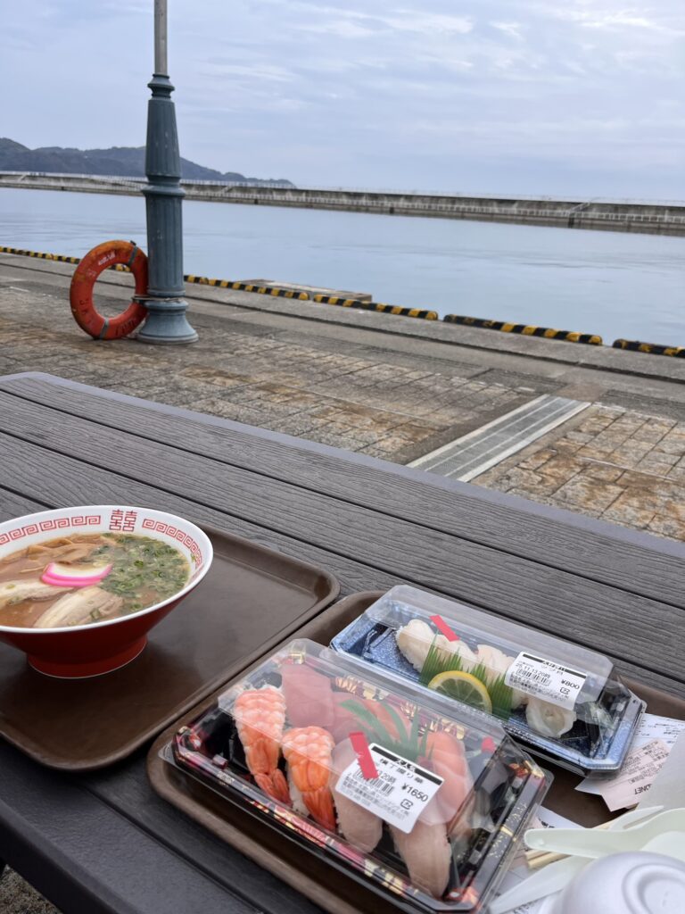 黒潮市場で購入した寿司と和歌山ラーメンを海沿いのベンチで並べた様子