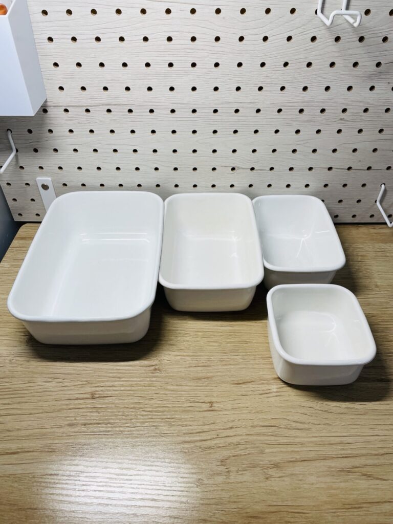 大中小のサイズがそろったホーロー保存容器を木製カウンターの上に並べている様子。