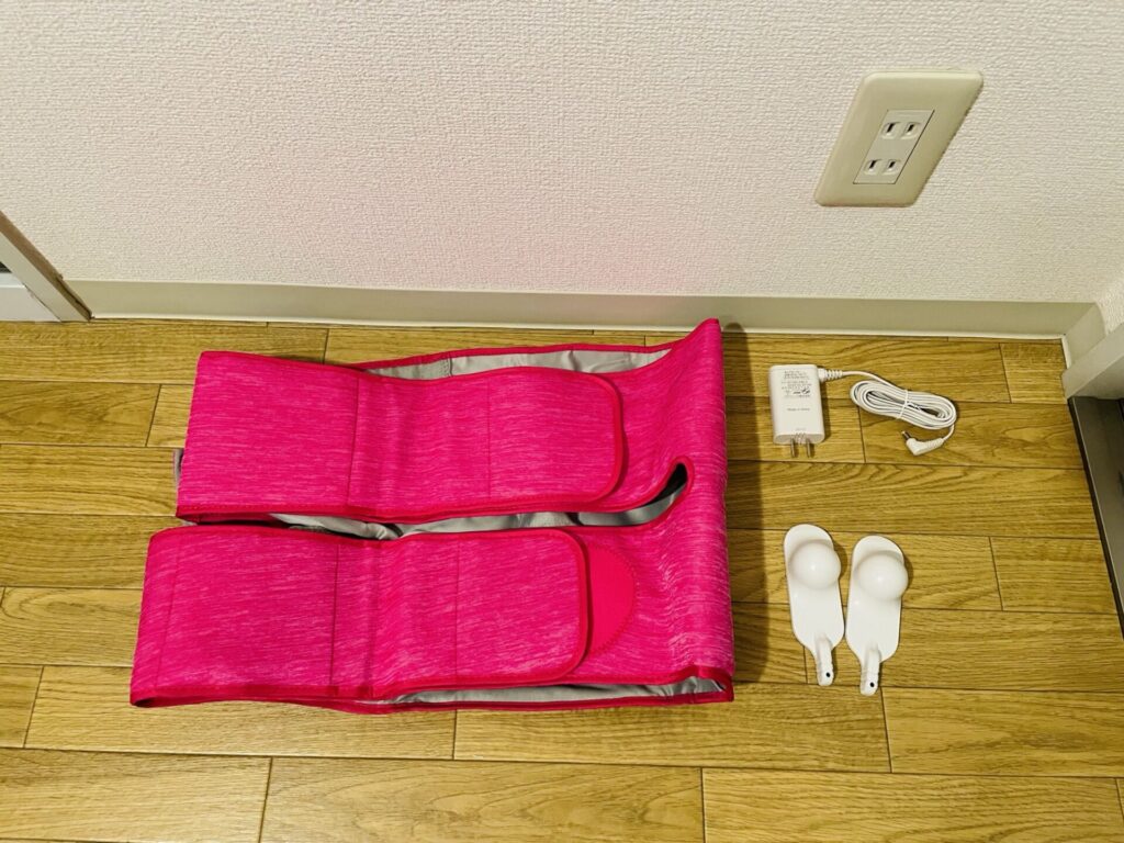 パナソニック骨盤おしりリフレEW-CRA79の本体、ACアダプター、付属品を床に並べた状態。
