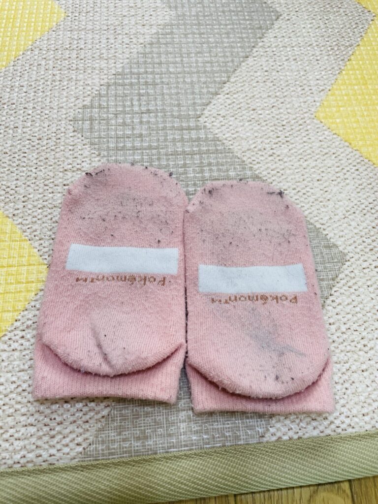 毛玉が多く付いた子どものピンクの靴下を並べて写した写真。