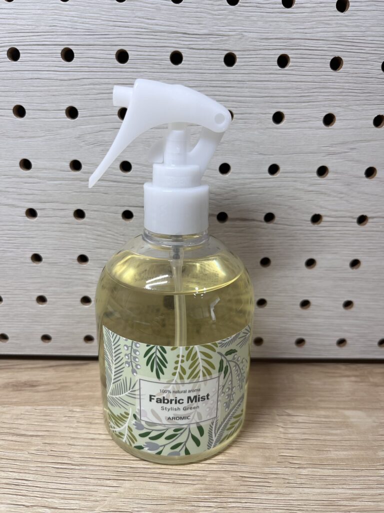 アロミックスタイルのファブリックミスト「スタイリッシュグリーン」のボトル外観。白いスプレーノズル付きの透明ボトルに、植物柄のラベルが貼られている。