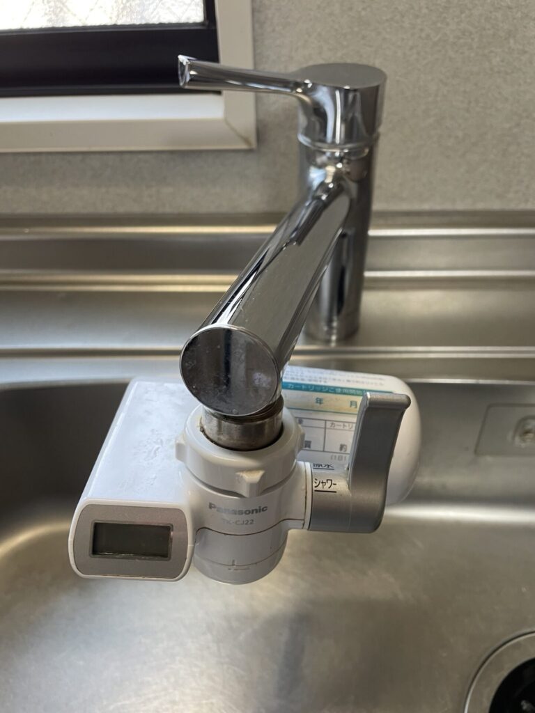 パナソニックの旧型浄水器TK-CJ22をキッチンの蛇口に取り付けて使用している様子。
