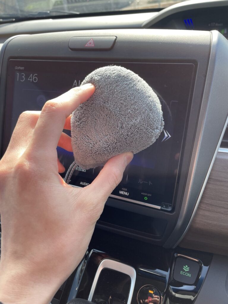 セリアの車内掃除用マイクロファイバークリーナーでナビ画面周りを掃除している様子。
