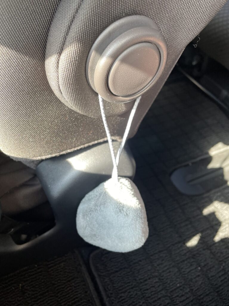 セリアの車内掃除用マイクロファイバークリーナーをシート横に掛けて収納している様子。