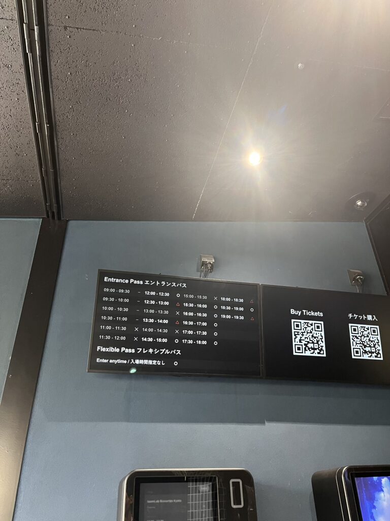 チームラボ京都の入口にある入場時間ごとのエントランスパス案内と、チケット購入用QRコードや購入機が並ぶ様子。