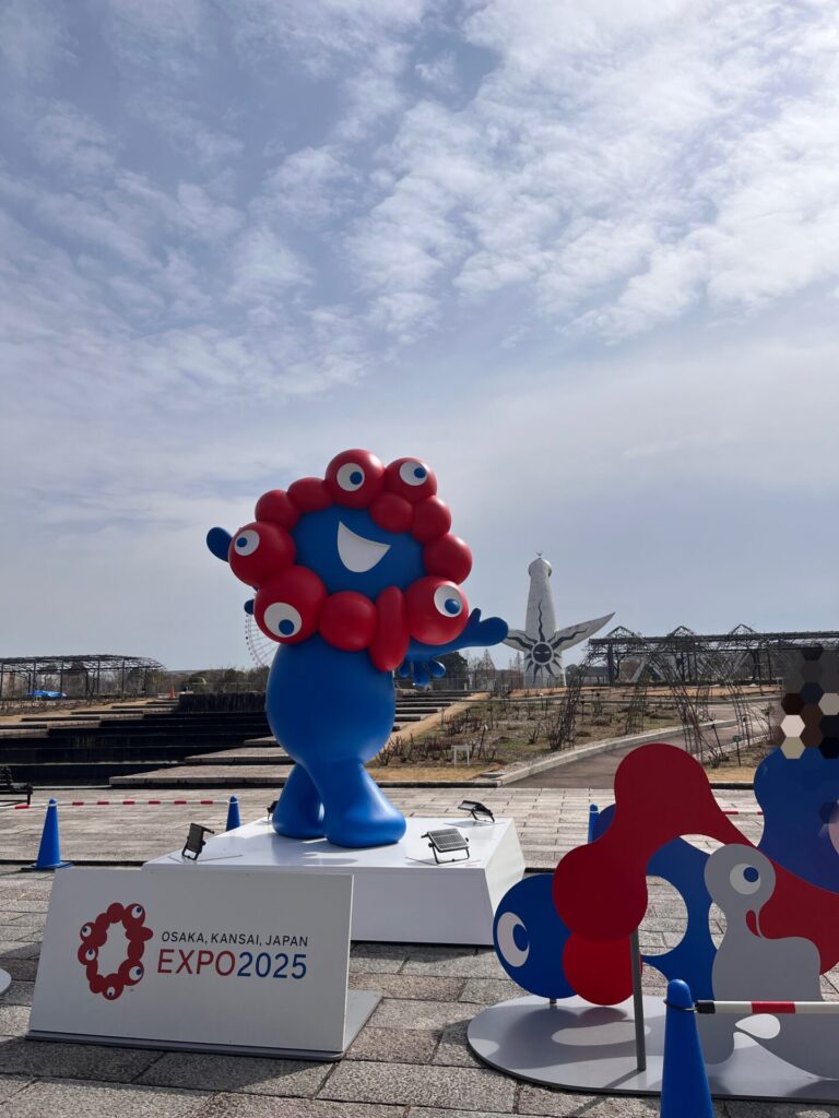 万博記念公園の平和のバラ園前に設置されたミャクミャクのモニュメントと太陽の塔