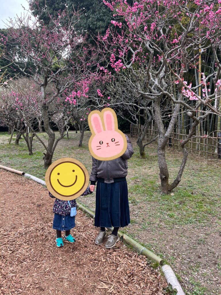 万博記念公園の梅林で咲き始めた梅の木の前に立つ親子の様子