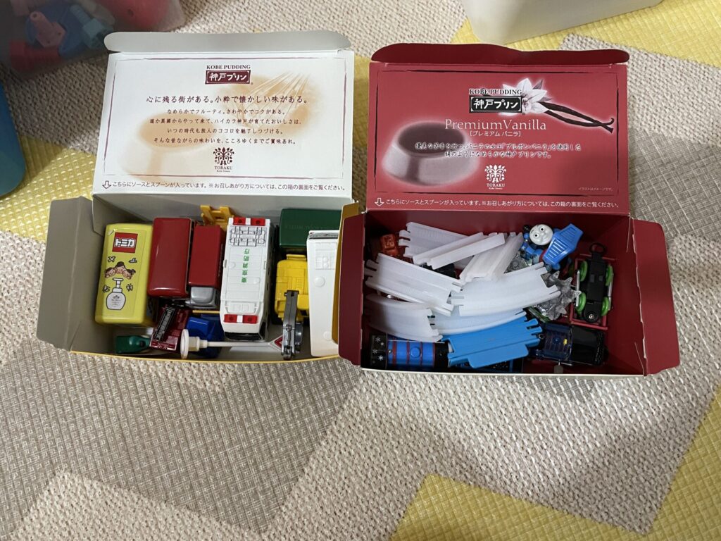 プリンの空き箱にトミカやパーツをまとめて収納していた状態