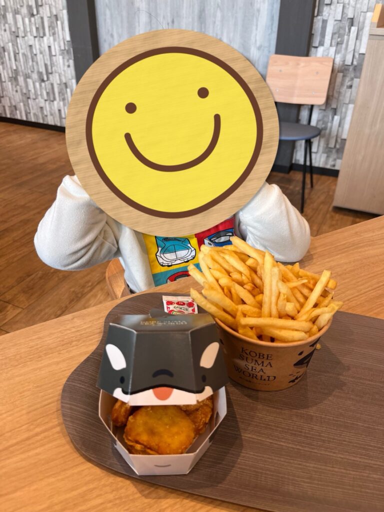 須磨シーワールドのフードコートで、ポテトとチキンのメニューを前に座る子ども。