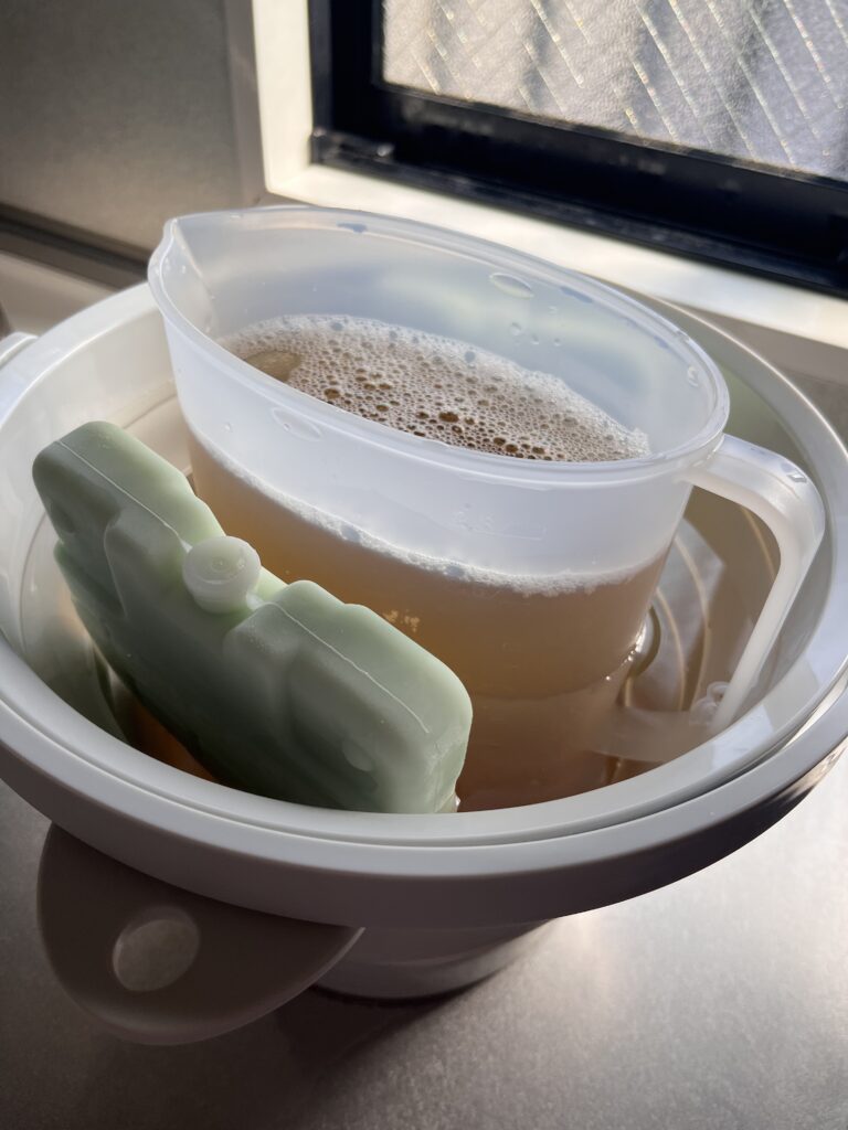 折りたたみバケツに水を張り、冷水筒と保冷剤を入れて麦茶を急冷している様子