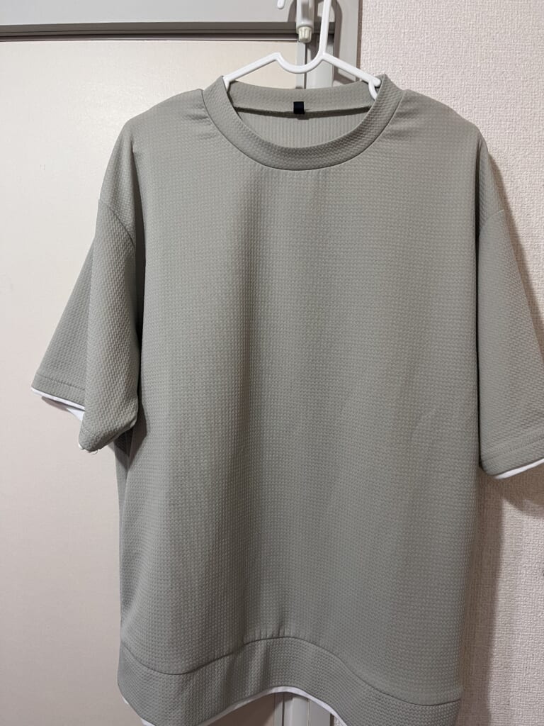 繰り返し洗濯・乾燥機を使用したcocaのメンズライトエンボスTシャツを、ハンガーに掛けた写真。