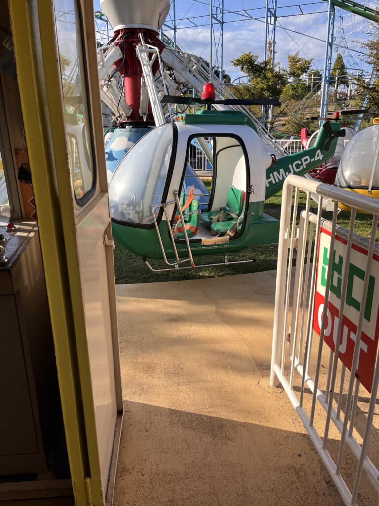 姫路セントラルパークのスカイヘリの乗り場にある、ドアが開いた緑色のヘリコプター型の乗り物