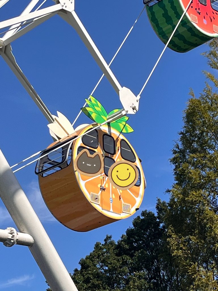 神戸おとぎの国で青空の下を上がるフルーツ型の観覧車のゴンドラ